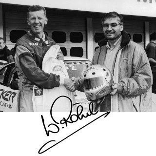 Walter Röhrl übergibt dem 2. Vorstand Achim Link seine Fahrerjacke, seinen Fahreroverall sowie seinen Fahrerhelm zur Versteigerung für einen guten Zweck